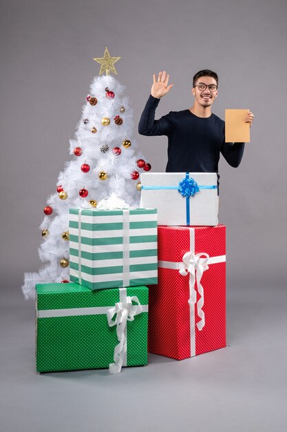 灰色の机の上の休日のプレゼントと正面図若い男性新年の人間の贈り物のクリスマス