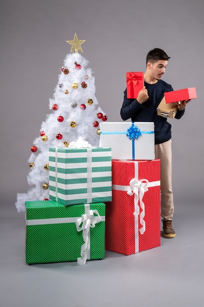 Front view young male with holiday presents on a grey