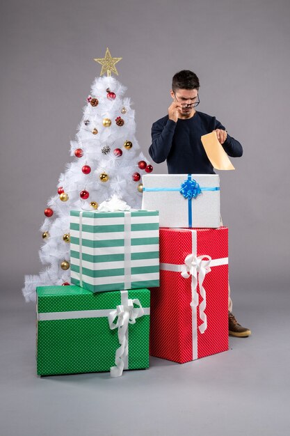 Front view young male with holiday presents on grey