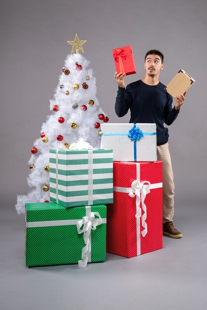 Front view young male with holiday presents on the grey