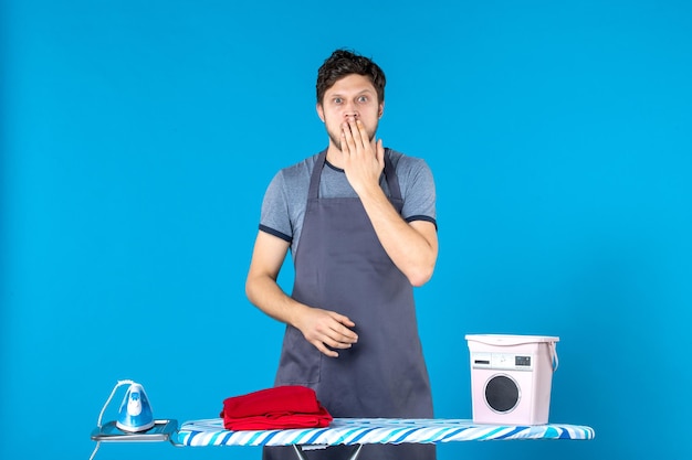 Front view young male with ironing board on blue background housework iron laundry cleaning washing machine man color