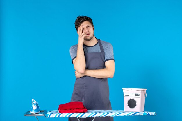 Front view young male with ironing board on blue surface