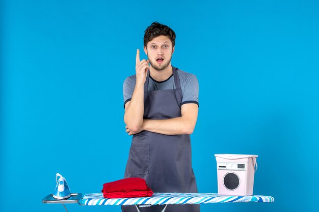 Front view young male with ironing board on the blue surface