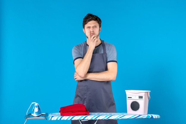 Front view young male with ironing board thinking on blue background housework laundry cleaning washing machine man color iron