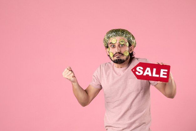 front view young male with mask on his face holding sale nameplate on pink background