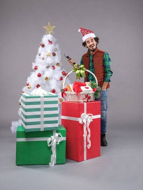 Front view young male with mic around presents on grey floor new year gift christmas