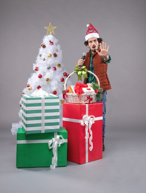 Front view young male with mic around presents on grey