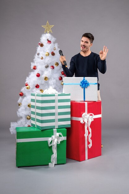 Front view young male with mic and presents on grey