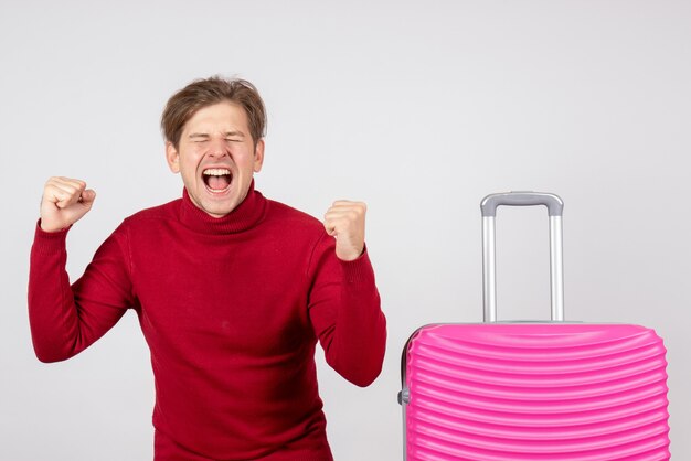 Front view of young male with pink bag emotionally rejoicing on the white wall