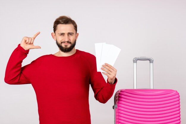 분홍색 가방과 흰 벽 색상 여행 휴가 비행 항해 관광에 티켓을 들고 전면보기 젊은 남성