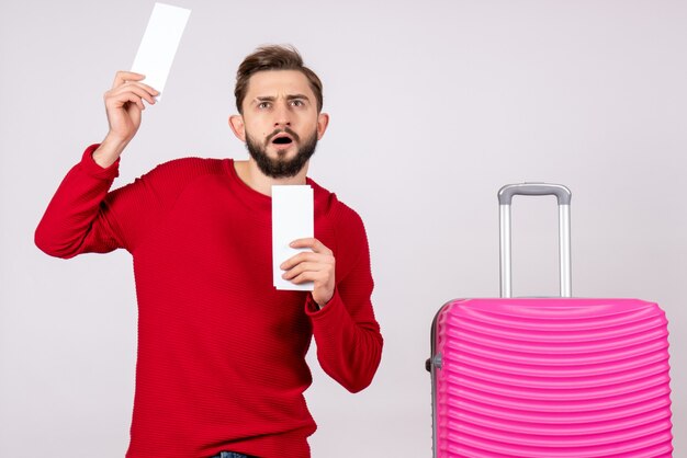 분홍색 가방과 흰 벽 여행 컬러 휴가 비행 항해 여름 관광에 티켓을 들고 전면보기 젊은 남성