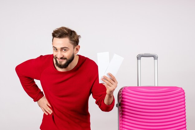 Front view young male with pink bag and holding tickets on white wall voyage flight color trip tourist emotion photo