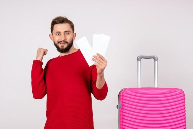 Front view young male with pink bag and holding tickets on white wall voyage flight color trip tourist vacation emotion photo