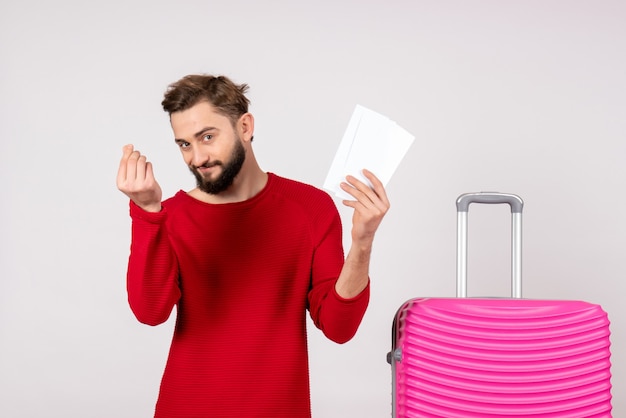 Front view young male with pink bag and holding tickets on a white wall voyage flight color trip tourist vacation photo