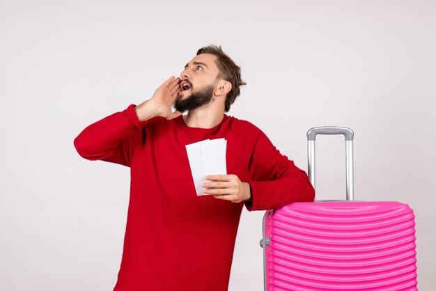 Front view young male with pink bag and holding tickets on white wall voyage flight color trip tourist vacation photos