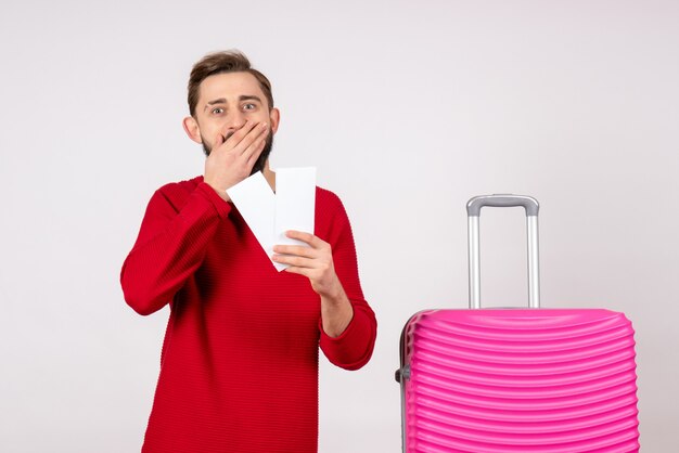 Front view young male with pink bag and holding tickets on white wall voyage flight color trip tourists vacation emotion photo