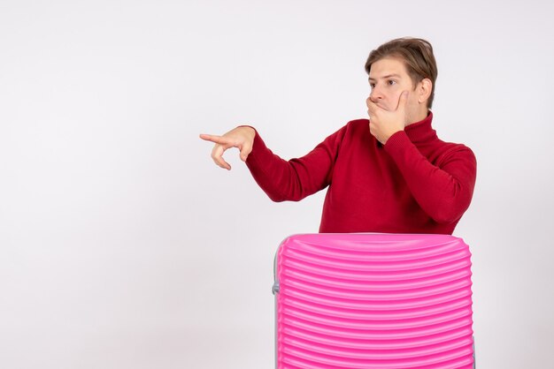 Foto gratuita giovane maschio di vista frontale con la borsa rosa che guarda scioccantemente a qualcosa su fondo bianco