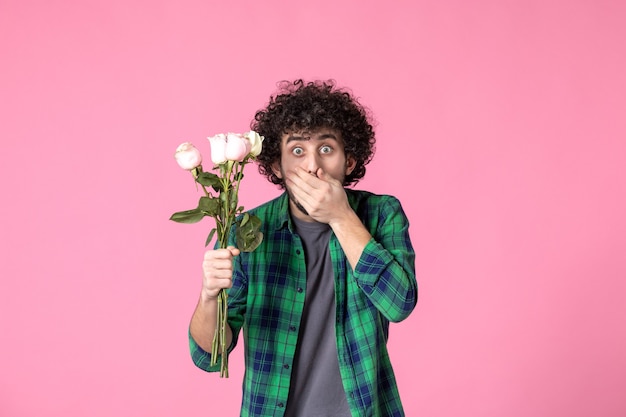 Front view young male with pink roses as present for womens day on pink color