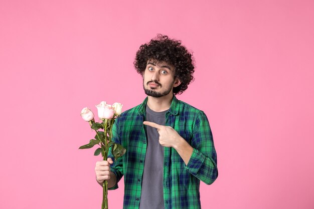 Front view young male with pink roses as present for womens day on pink color