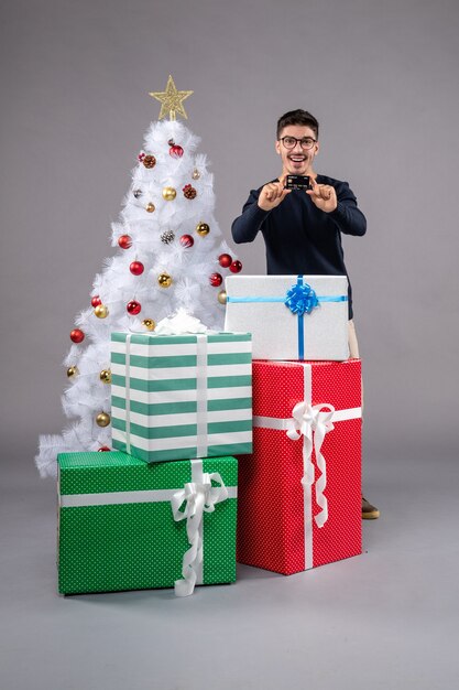 Front view young male with presents and bank card on grey desk holiday new year xmas