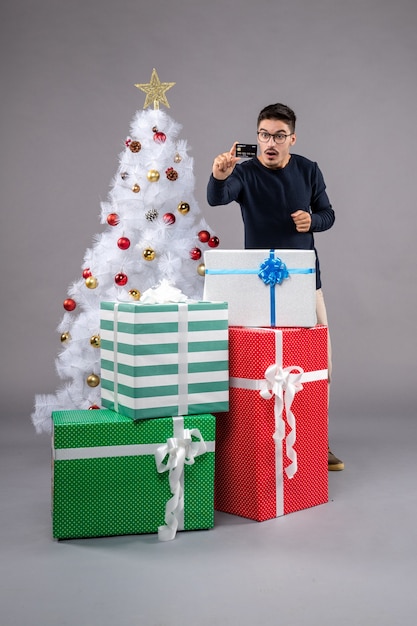 Front view young male with presents and bank card on a grey 