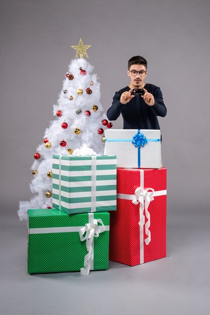 灰色のプレゼントと銀行カードを持つ若い男性の正面図