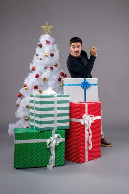 Front view young male with presents and camera on grey