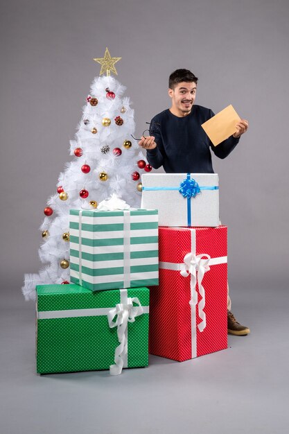 Front view young male with presents and envelop on the grey