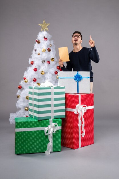 プレゼントとライトデスクの休日の新年のクリスマスに包む正面図の若い男性
