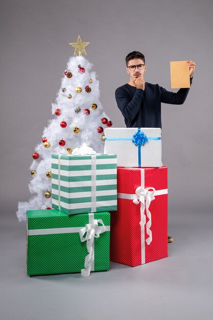 Front view young male with presents and envelop on a light