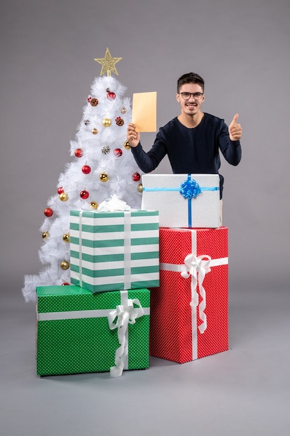 Вид спереди молодой мужчина с подарками и конвертом на свет
