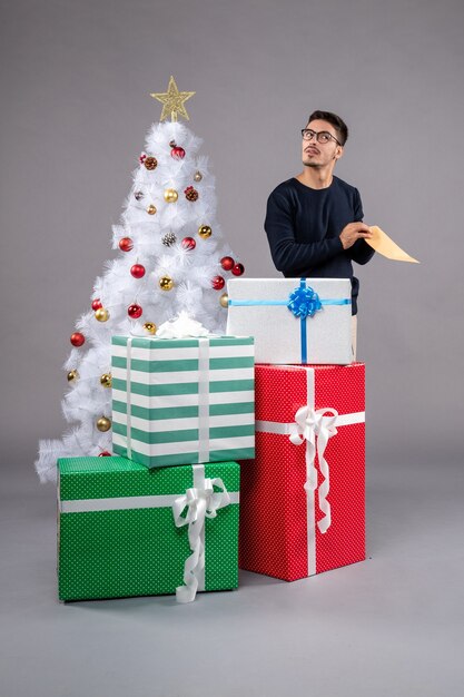 Front view young male with presents and envelop on a light