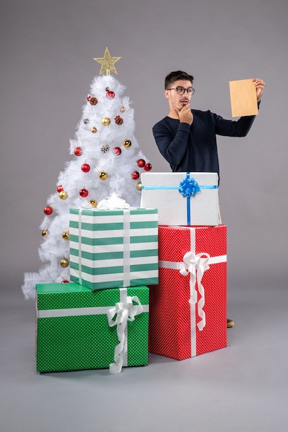 Front view young male with presents and envelop on light