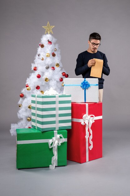 Вид спереди молодой мужчина с подарками и конвертом на свет