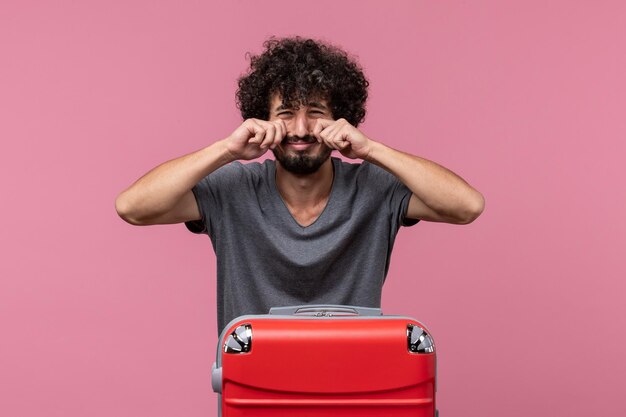 Front view young male with red bag preparing for trip crying on pink space