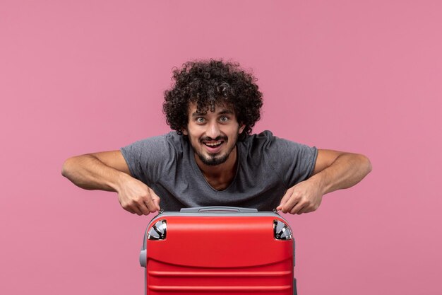 Front view young male with red bag preparing for trip on a pink space