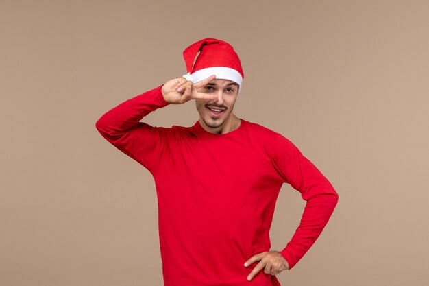 Front view young male with red christmas cape on brown background emotion christmas holiday