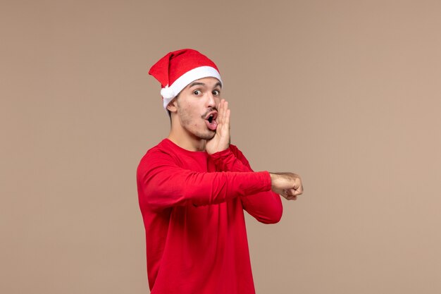 Front view young male with red christmas cape on brown background emotions christmas holiday