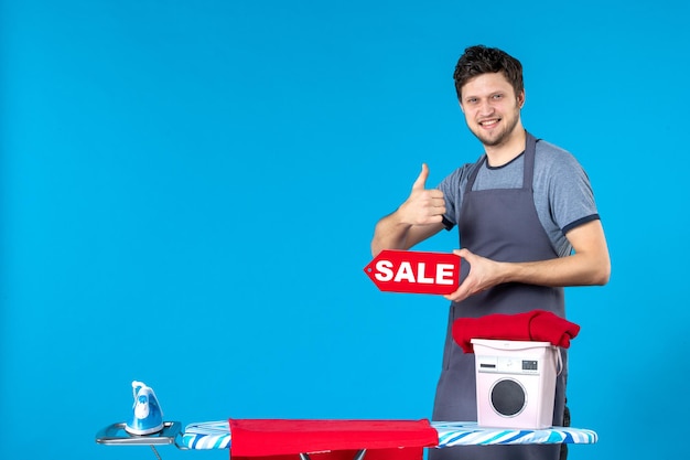 Free photo front view young male with red sale writing in his hands on blue background housework iron shopping washing machine cleaning