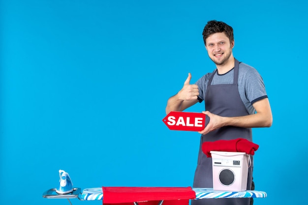 Front view young male with red sale writing in his hands on blue background housework iron shopping washing machine cleaning