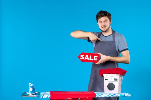 正面図青の背景に彼の手で書いている赤いセールの若い男性家事洗濯アイロンショッピング洗濯機のクリーニング