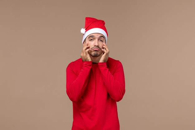 茶色の背景の休日のクリスマスの感情に悲しい表情で若い男性の正面図