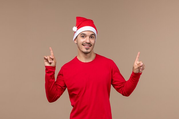 Вид спереди молодой мужчина с улыбающимся выражением лица на коричневом фоне праздник рождественские эмоции