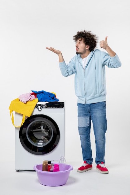 Free photo front view of young male with washer and dirty clothes on a white wall