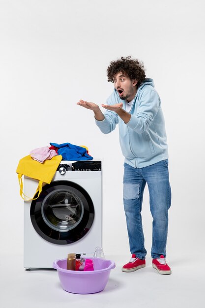 Free photo front view of young male with washer and dirty clothes on the white wall