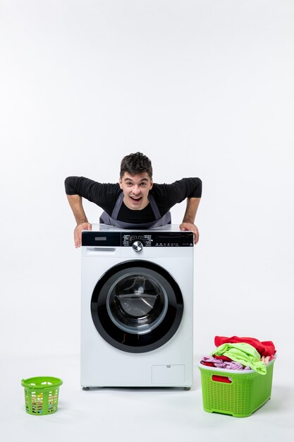 Free photo front view of young male with washer and dirty clothes on white wall