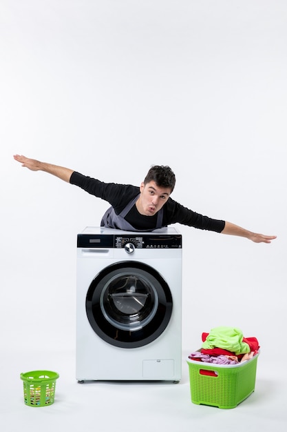 Free photo front view of young male with washer and dirty clothes on white wall