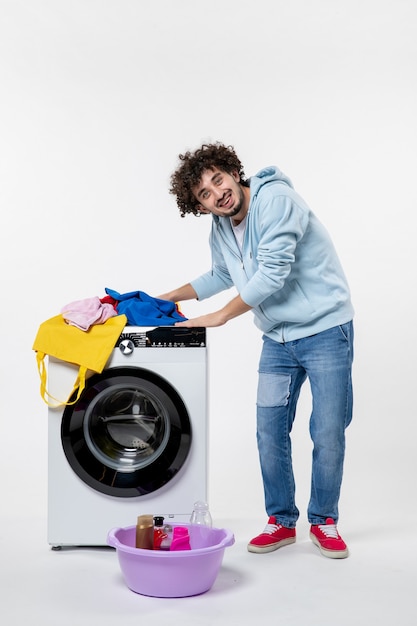 Free photo front view of young male with washer and dirty clothes on white wall