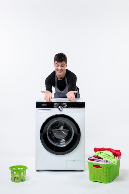 Free photo front view of young male with washer and dirty clothes on white wall