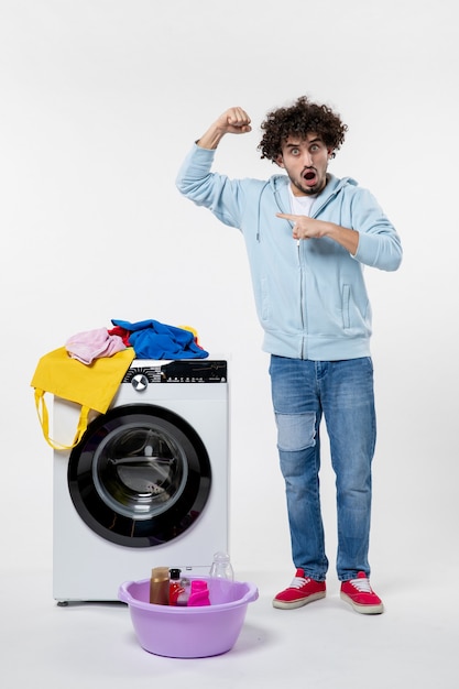 Free photo front view of young male with washer flexing on white wall